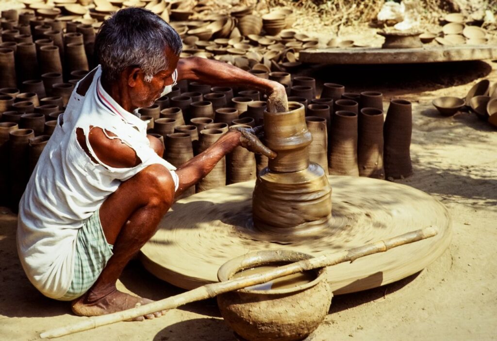 A traditional Indian potter skillfully crafting clay pots on a spinning wheel, showcasing cultural heritage.